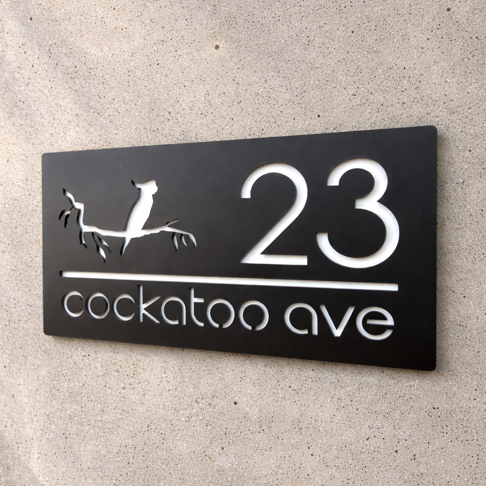 House number sign with '23 cockatoo ave' on a concrete wall