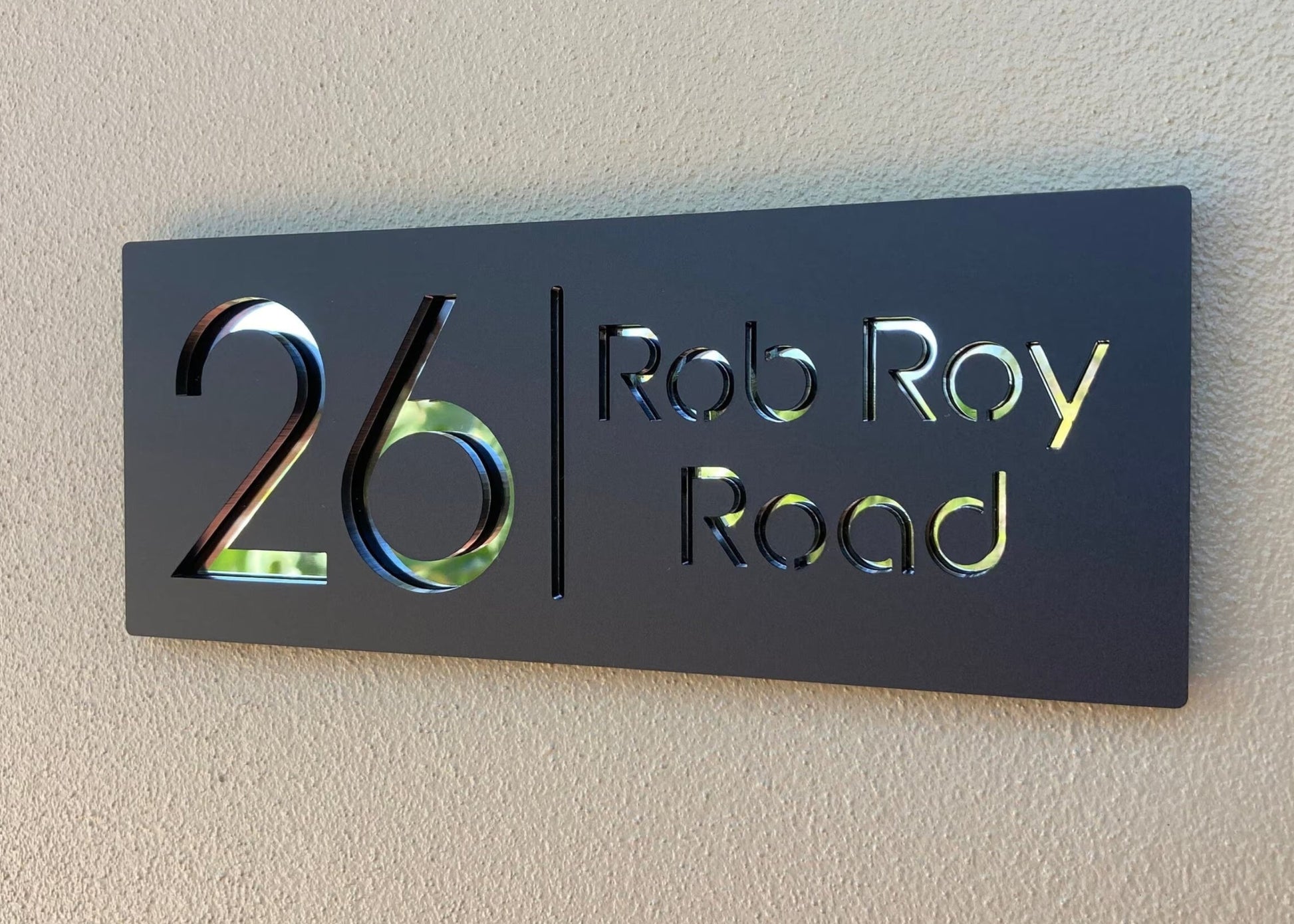 House number sign with '26 Rob Roy Road' on a beige wall