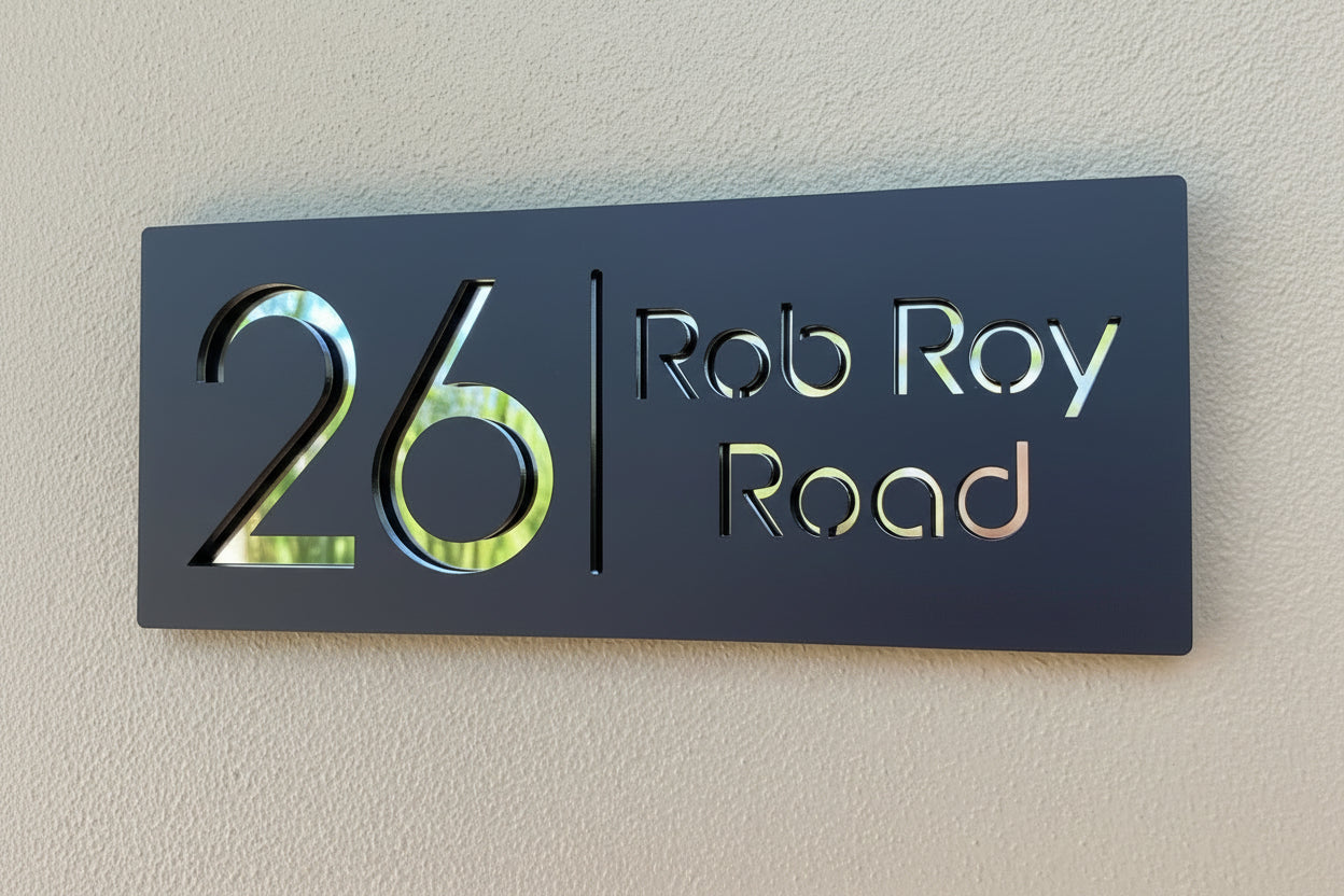 House number sign with '26 Rob Ray Road' on a beige wall