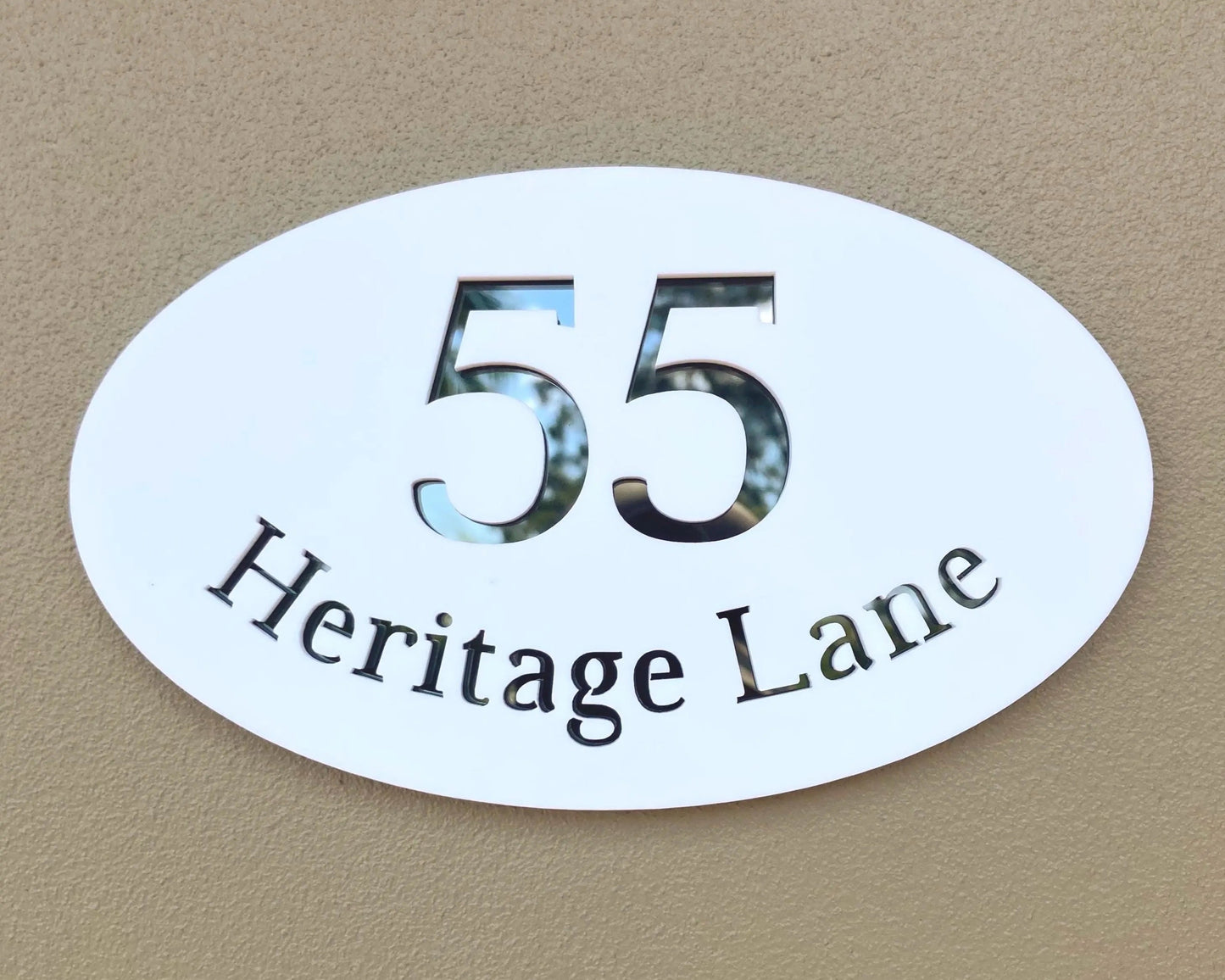 Oval-shaped house number sign with '55 Heritage Lane' on a beige background